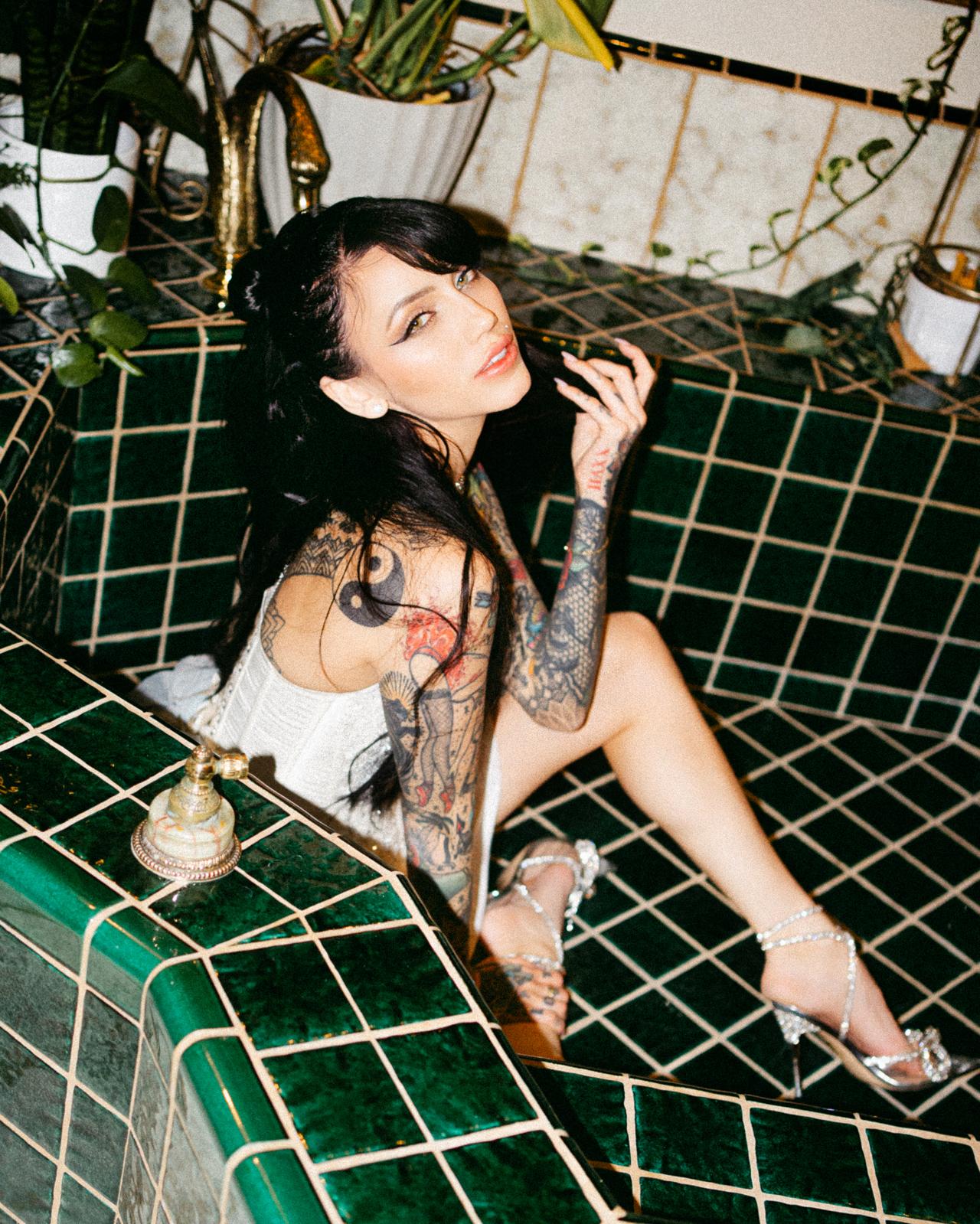 Divinity wearing bridal dress in dark green tiled washroom